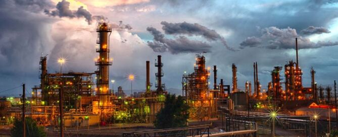 An oil refinery set against an ominous cloudy sky.
