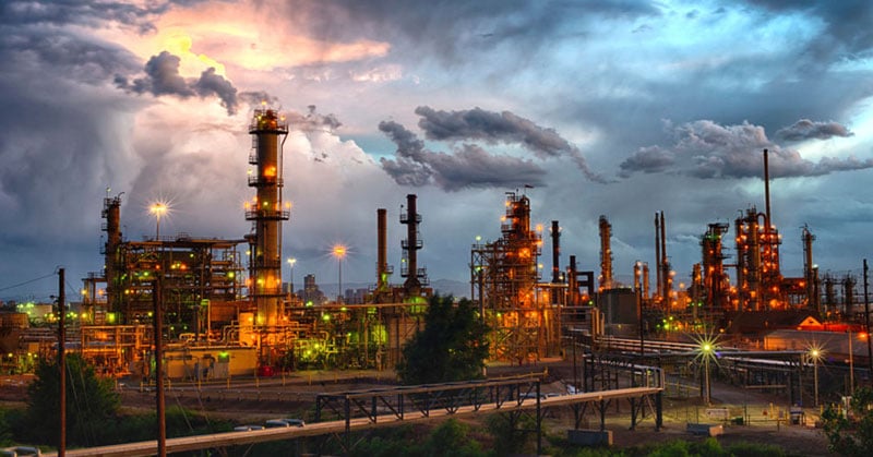 An oil refinery set against an ominous cloudy sky.