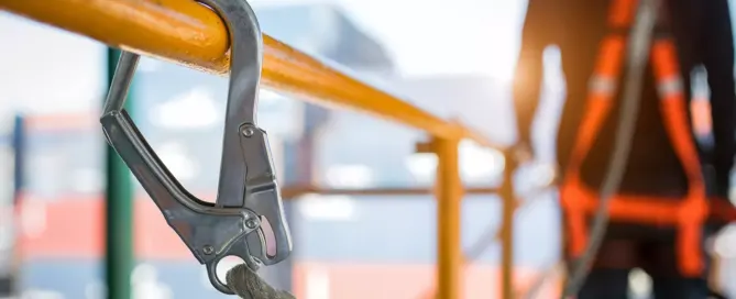 Industrial worker wearing safety harness and safety line while working at a high elevation in a construction site