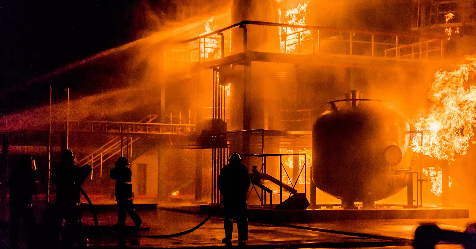 firefighters using water hose to extinguish fire